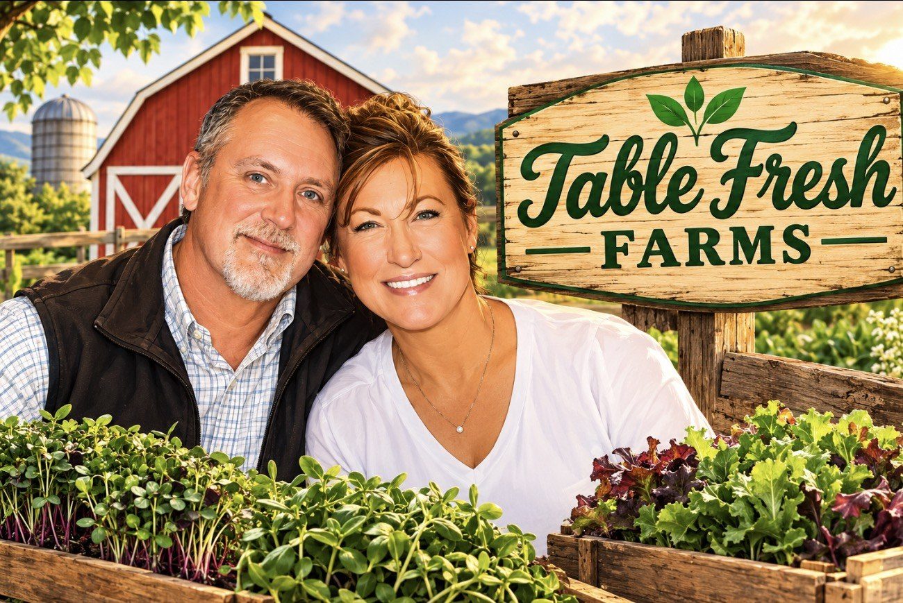 Darin and Sonya beside the Table Fresh Farms sign with trays of fresh greens